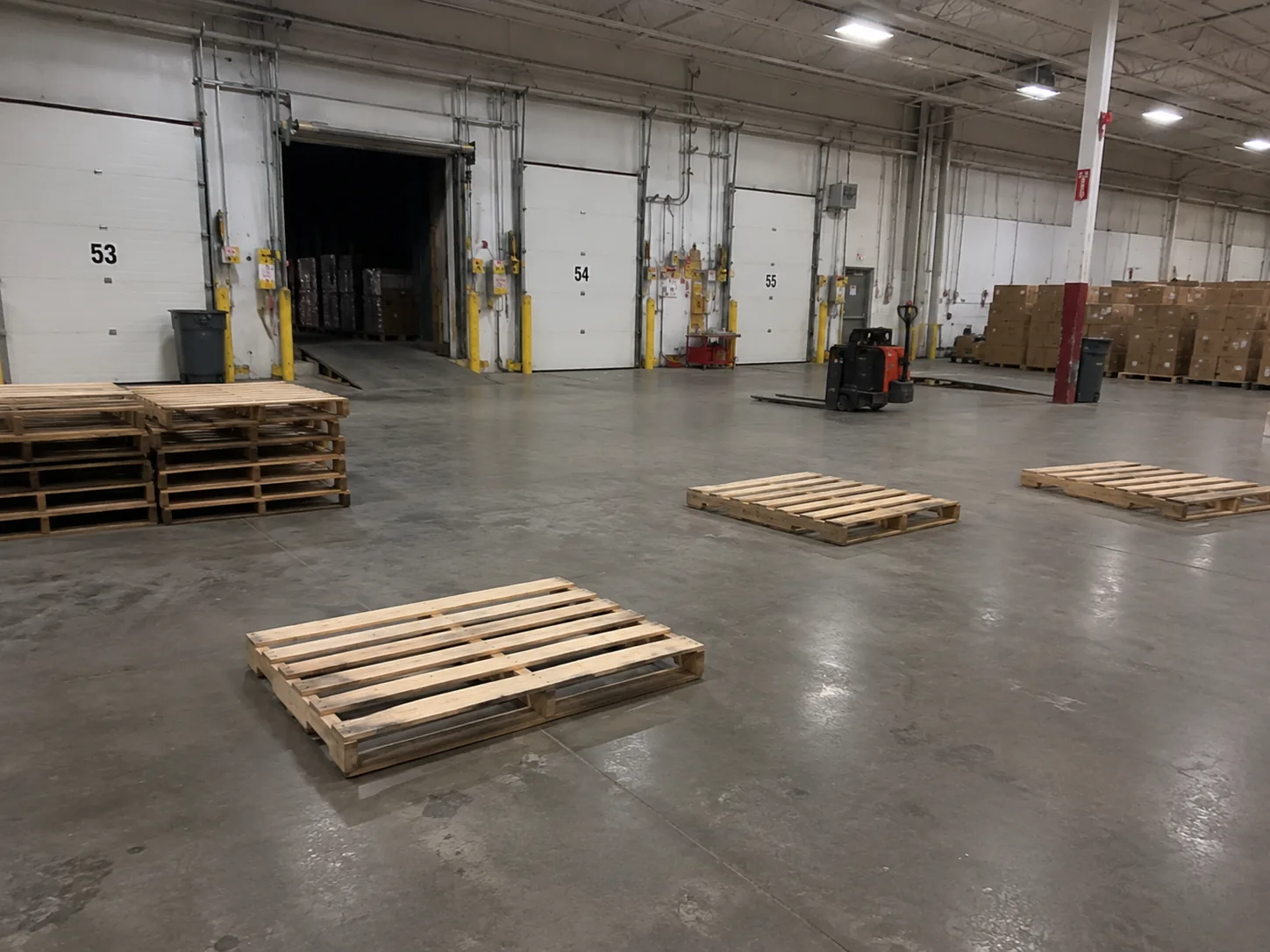 A warehouse loading dock with empty wooden pallets stacked against the wall — the kind of scene that sits between "we're full" and "we have space we can't see."