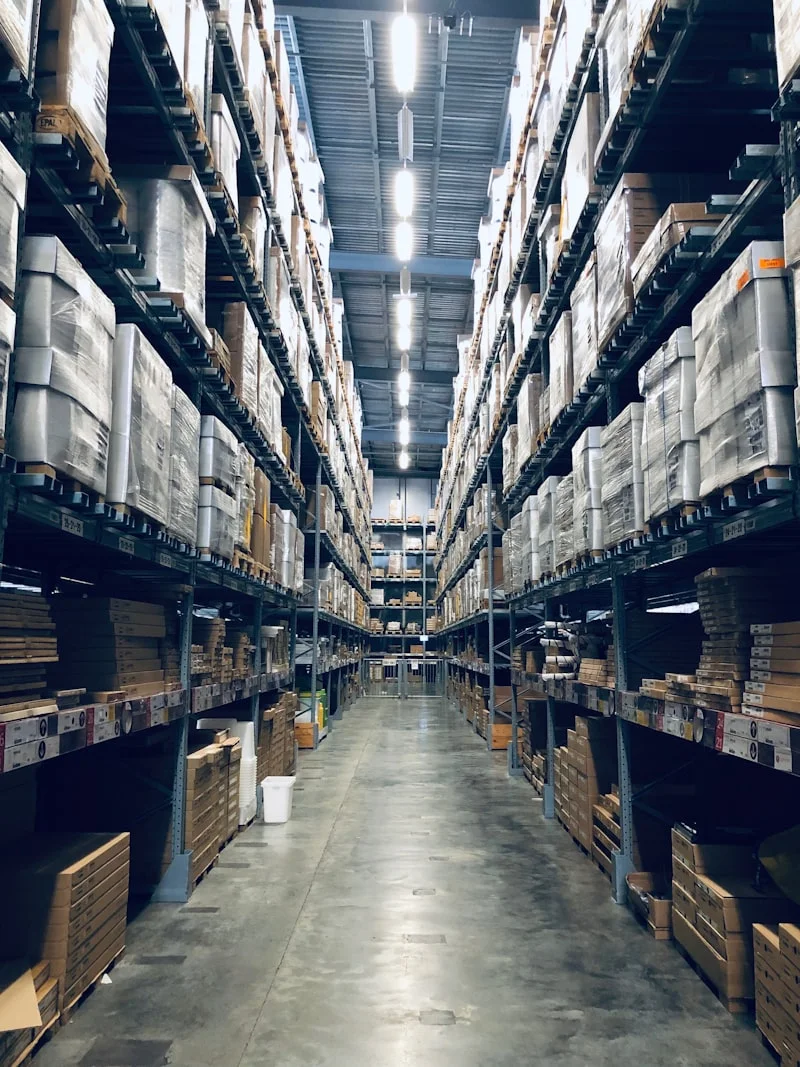 A long warehouse aisle lined with tall racking and stacked cartons — the kind of space that looks fully utilized at a glance but often hides slow movers, dead bins, and honeycombing the WMS can't see.